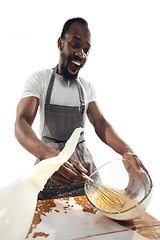 Image showing Amazing african-american man preparing unbelievable food with close up action, details and bright emotions, professional cook. Preparing omelet, mixing eggs with splashing milk