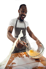 Image showing Amazing african-american man preparing unbelievable food with close up action, details and bright emotions, professional cook. Preparing omelet, mixing eggs with splashing milk