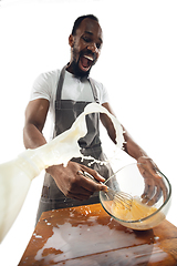 Image showing Amazing african-american man preparing unbelievable food with close up action, details and bright emotions, professional cook. Preparing omelet, mixing eggs with splashing milk