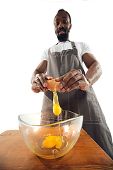 Image showing Amazing african-american man preparing unbelievable food with close up action, details and bright emotions, professional cook. Preparing omelet, mixing eggs