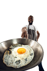 Image showing Amazing african-american man preparing unbelievable food with close up action, details and bright emotions, professional cook. Preparing fried eggs