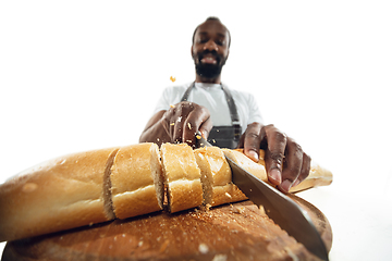 Image showing Amazing african-american man preparing unbelievable food with close up action, details and bright emotions, professional cook. Cutting bread