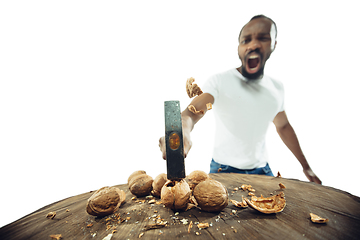 Image showing Amazing african-american man preparing unbelievable food with close up action, details and bright emotions, professional cook. Cracking nuts