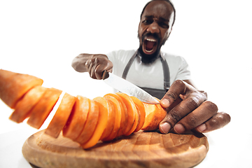 Image showing Amazing african-american man preparing unbelievable food with close up action, details and bright emotions, professional cook. Cutting carrot on the fly
