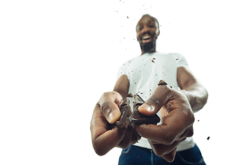 Image showing Amazing african-american man preparing unbelievable food with close up action, details and bright emotions, professional cook. Cracking chocolate