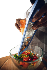 Image showing Amazing african-american man preparing unbelievable food with close up action, details and bright emotions, professional cook. Cutting carrot to salad