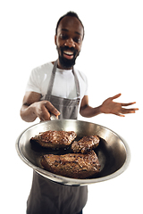 Image showing Amazing african-american man preparing unbelievable food with close up action, details and bright emotions, professional cook. Preparing fried meat, steakes