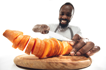 Image showing Amazing african-american man preparing unbelievable food with close up action, details and bright emotions, professional cook. Cutting carrot on the fly