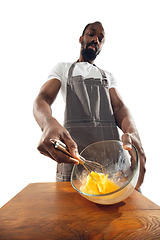 Image showing Amazing african-american man preparing unbelievable food with close up action, details and bright emotions, professional cook. Preparing omelet, mixing eggs