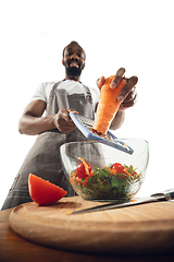 Image showing Amazing african-american man preparing unbelievable food with close up action, details and bright emotions, professional cook. Cutting carrot to salad