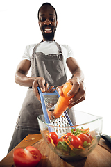 Image showing Amazing african-american man preparing unbelievable food with close up action, details and bright emotions, professional cook. Cutting carrot to salad