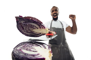 Image showing Amazing african-american man preparing unbelievable food with close up action, details and bright emotions, professional cook. Cutting cabbage on the fly