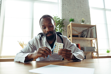 Image showing Doctor advising the patient online with laptop. African-american doctor during his videocall, work with patients, explaining recipes for drug.