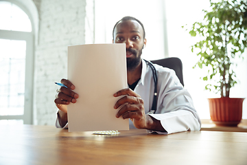 Image showing Doctor advising the patient online with laptop. African-american doctor during his videocall, work with patients, explaining recipes for drug.