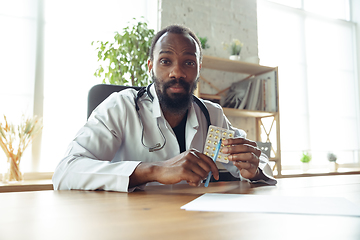 Image showing Doctor advising the patient online with laptop. African-american doctor during his videocall, work with patients, explaining recipes for drug.