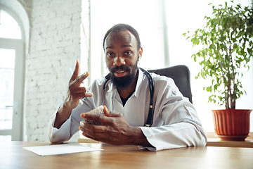 Image showing Doctor advising the patient online with laptop. African-american doctor during his videocall, work with patients, explaining recipes for drug.