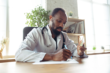 Image showing Doctor advising the patient online with laptop. African-american doctor during his videocall, work with patients, explaining recipes for drug.