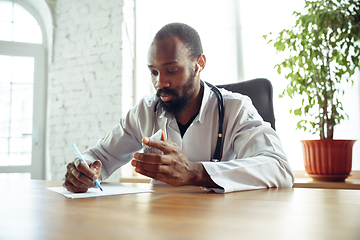 Image showing Doctor advising the patient online with laptop. African-american doctor during his videocall, work with patients, explaining recipes for drug.