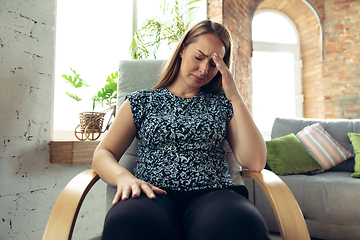 Image showing Young woman gesturing during a video conference in the living room. Sad, upset, headache