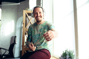 Image showing Young man gesturing during a video conference in the living room. Attented listening