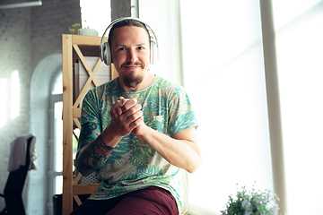 Image showing Young man gesturing during a video conference in the living room. Support gesture, smiling