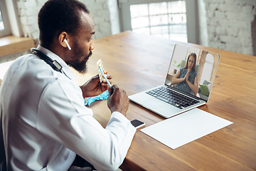 Image showing Doctor advising the patient online with laptop. African-american doctor during his videocall, work with patients, explaining recipes for drug.