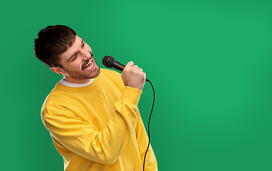 Image showing man in yellow sweatshirt with microphone singing