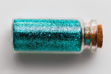 Image showing blue glitters in bottle over white background