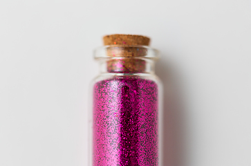 Image showing pink glitters in bottle over white background