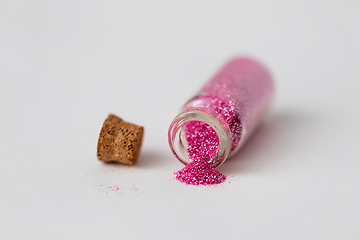 Image showing pink glitters poured from small glass bottle