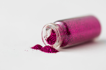 Image showing pink glitters poured from small glass bottle