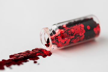 Image showing red glitters poured from small glass bottle