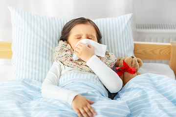 Image showing sick girl lying in bed and blowing nose at home