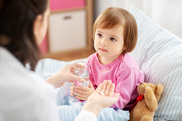 Image showing doctor giving medicine to sick girl in bed at home