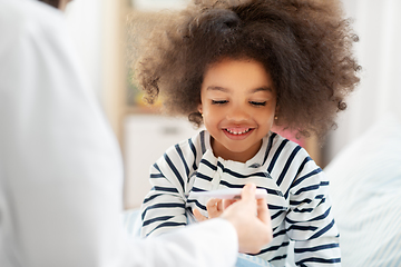 Image showing doctor showing thermometer to smiling sick girl