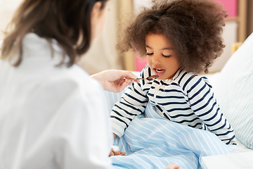 Image showing doctor giving medicine to sick girl in bed at home