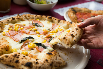 Image showing Hand taking out of sliced of pizza