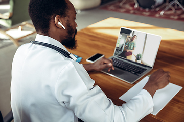 Image showing Doctor advising the patient online with laptop. African-american doctor during his videocall, work with patients, explaining recipes for drug.