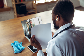 Image showing Doctor advising the patient online with laptop. African-american doctor during his videocall, work with patients, explaining recipes for drug.