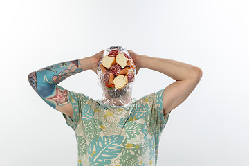 Image showing Male face covered with oilcloth, cellophane and unhealthy food, hard to breathe. People lost their faces, can\'t notice the environmental pollution made by themself.