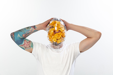 Image showing Male face covered with oilcloth, cellophane and unhealthy food, hard to breathe. People lost their faces, can\'t notice the environmental pollution made by themself.