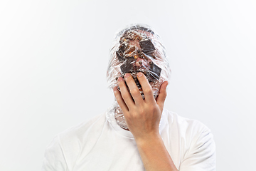 Image showing Male face covered with oilcloth, cellophane and unhealthy food, hard to breathe. People lost their faces, can\'t notice the environmental pollution made by themself.