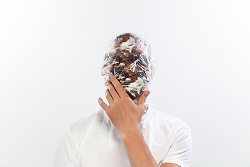 Image showing Male face covered with oilcloth, cellophane and unhealthy food, hard to breathe. People lost their faces, can\'t notice the environmental pollution made by themself.