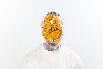 Image showing Male face covered with oilcloth, cellophane and unhealthy food, hard to breathe. People lost their faces, can\'t notice the environmental pollution made by themself.