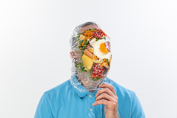 Image showing Male face covered with oilcloth, cellophane and unhealthy food, hard to breathe. People lost their faces, can\'t notice the environmental pollution made by themself.