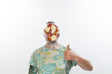 Image showing Male face covered with oilcloth, cellophane and unhealthy food, hard to breathe. People lost their faces, can\'t notice the environmental pollution made by themself.