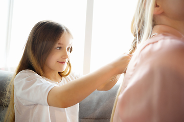 Image showing Mother and daughter, sisters have quite, beauty and fun day together at home. Comfort and togetherness. Making a hairstyle.