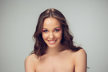 Image showing Close up of beautiful young woman with long healthy curly hair and bright make up isolated on grey studio backgroud, smiling with white teeth