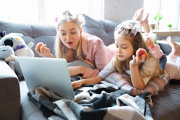 Image showing Mother and daughter, sisters have quite, beauty and fun day together at home. Comfort and togetherness. Watching series, eating healthy food, do a hairstyle