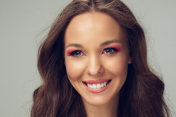 Image showing Close up of beautiful young woman with long healthy curly hair and bright make up isolated on grey studio backgroud, smiling with white teeth